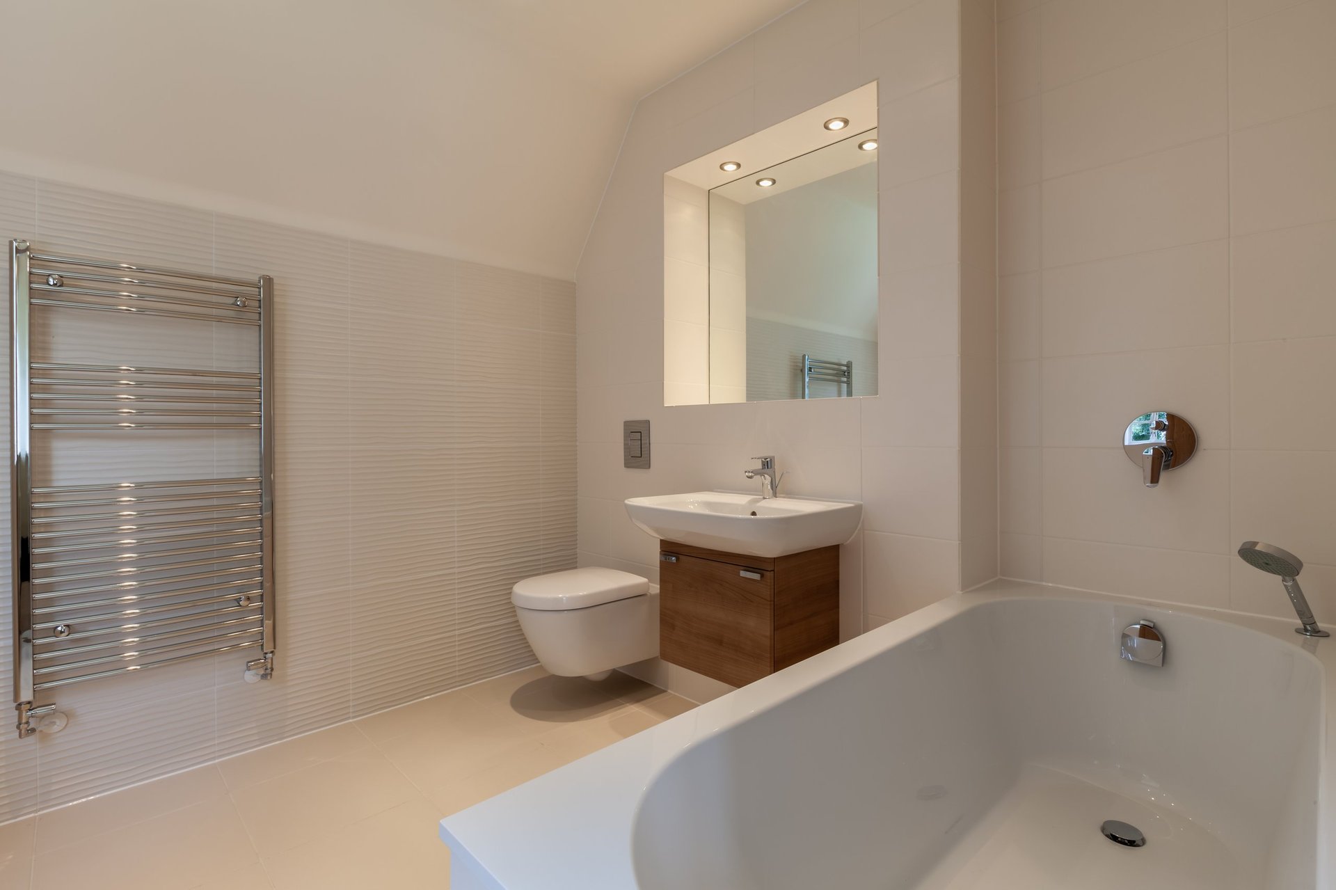 New modern bathroom suite with chrome towel rail, sink on wall mounted cupboard and inset mirror