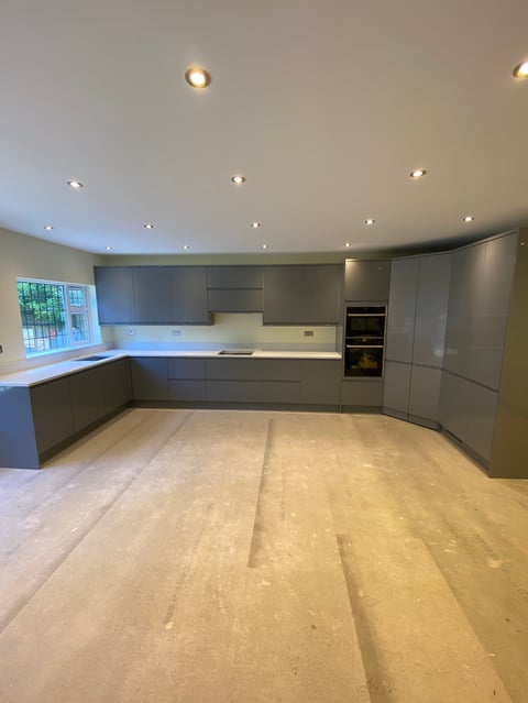 Modern kitchen with gray cabinetry, light wood flooring, recessed ceiling lights, and stainless steel appliances