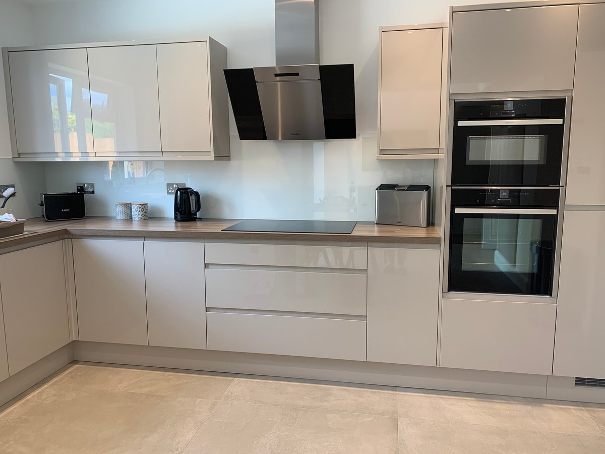 Modern kitchen with cream cabinets, stainless steel appliances, and white tile backsplash